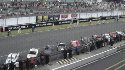 A Row Of Cars Are Parked On A Race Track With Richard Mille Advertisements GIF