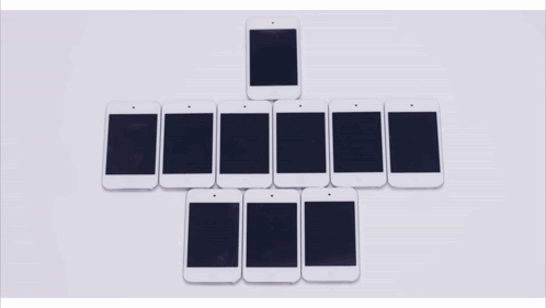 A Row Of Cell Phones Are Lined Up In A Row On A Table GIF