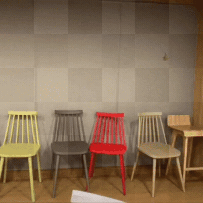 A Row Of Chairs Of Different Colors Are Lined Up In A Room GIF