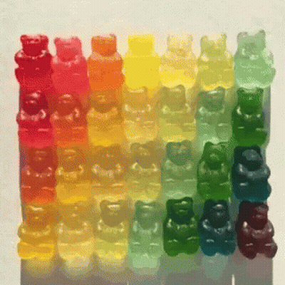 A Row Of Colorful Gummy Bears Are Lined Up In A Row GIF