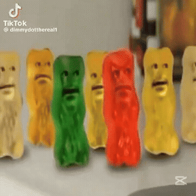 A Row Of Gummy Bears With Faces On Them Are Sitting On A Table . GIF