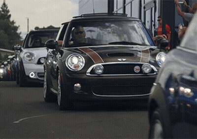 A Row Of Mini Cooper 'S Are Parked On A Street GIF