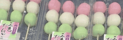 A Row Of Pink , White , And Green Balls On Sticks In Plastic Containers . GIF