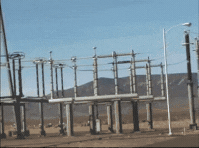 A Row Of Power Lines Are Lined Up In A Field With Mountains In The Background GIF