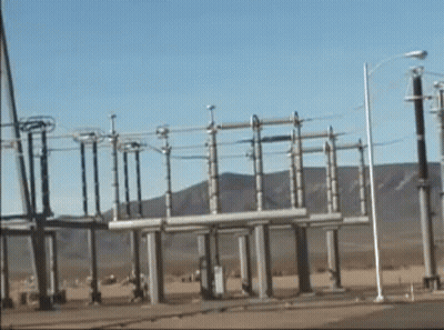 A Row Of Power Lines In A Field With Mountains In The Background . GIF