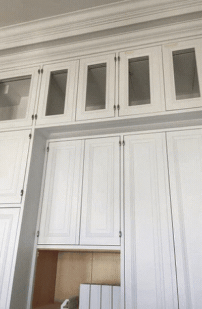 A Row Of White Cabinets With Glass Doors On Top GIF