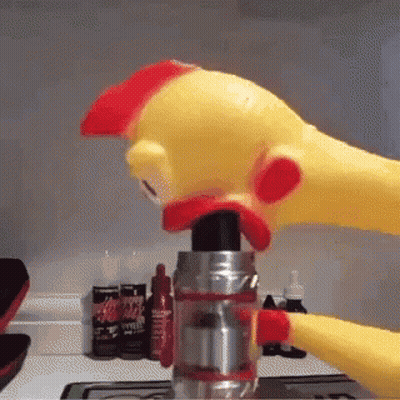A Rubber Chicken Is Holding A Bottle Of Ketchup In Its Mouth . GIF
