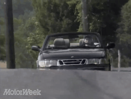 A Saab Convertible Is Driving Down A Road With Motorweek Written In The Corner GIF