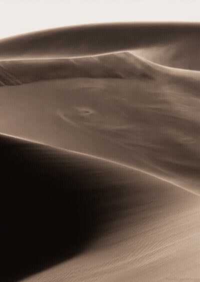 A Sand Dune With A White Sky In The Background GIF