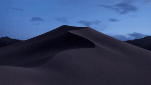 A Sand Dune With Mountains In The Background And A Purple Sky GIF