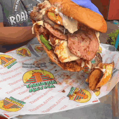 A Sandwich With A Lot Of Meat And Cheese Is On A Piece Of Paper That Says Taqueria Azteca On It GIF