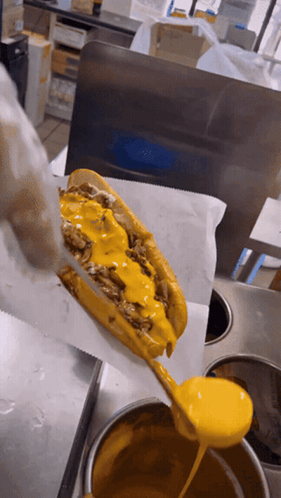 A Sandwich With Cheese And Meat Is Being Covered In Yellow Sauce GIF