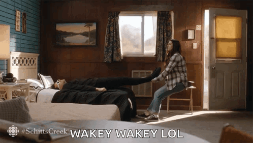 A Scene From Schitt 'S Creek Shows A Woman Stretching A Man 'S Legs GIF