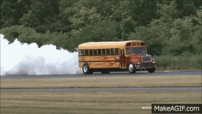 A School Bus Driving Down A Road With Smoke Coming Out Of It GIF