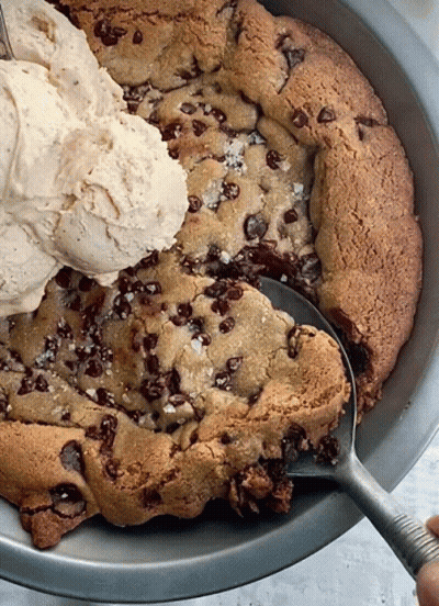 A Scoop Of Ice Cream Is Being Poured On Top Of A Cookie GIF