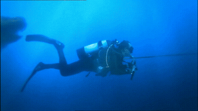 A Scuba Diver Is Swimming In A Blue Water GIF