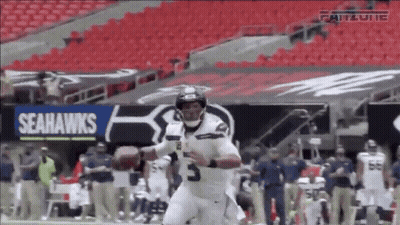 A Seahawks Football Player Is Running With A Ball GIF
