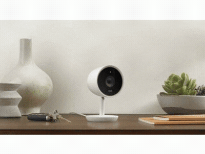 A Security Camera Is Sitting On Top Of A Wooden Table Next To A Vase And Keys . GIF