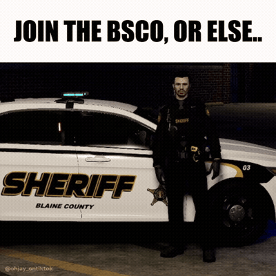 a sheriff stands in front of a blaine county sheriff car