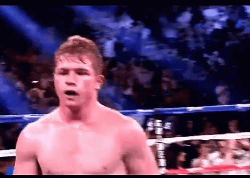 A Shirtless Boxer In A Boxing Ring With A Crowd In The Background GIF