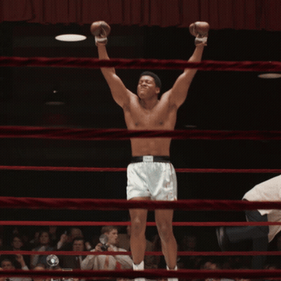 A Shirtless Boxer In A Ring With His Arms Up GIF