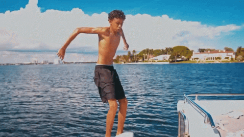 A Shirtless Boy In Black Shorts Jumps Into The Water GIF