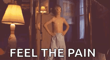 A Shirtless Boy Is Standing In Front Of A Lamp With His Hands On His Hips . GIF