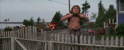 A Shirtless Boy Stands In Front Of A Fence GIF