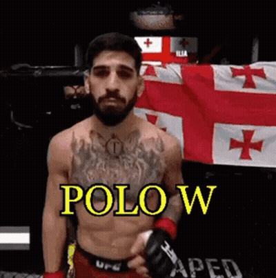 A Shirtless Fighter With A Beard Is Standing In Front Of A Flag And Holding A Glove . GIF