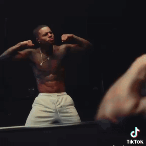 A Shirtless Man Flexes His Muscles In Front Of A Mirror With Tiktok Written On The Bottom Right GIF