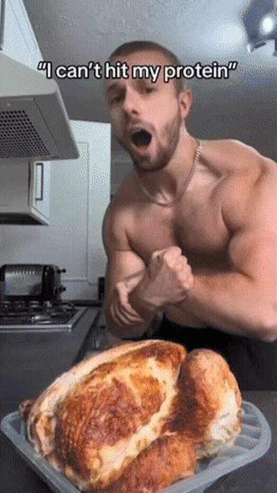 A Shirtless Man Flexes His Muscles In Front Of A Turkey That Says I Can 'T Hit My Protein GIF