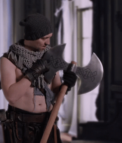 A Shirtless Man Holding A Large Axe With A Celtic Design On It GIF