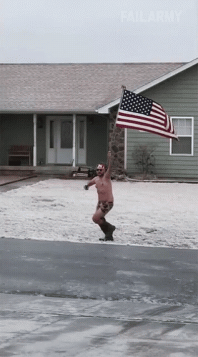A Shirtless Man Holding An American Flag In Front Of A House GIF