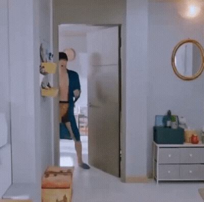A Shirtless Man In A Blue Robe And Underwear Is Dancing In A Room . GIF