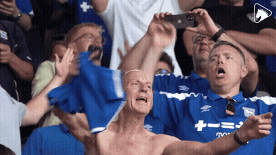 A Shirtless Man In A Crowd Is Wearing A Shirt That Says ' Umbro ' On It GIF