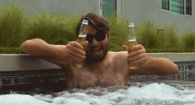 A Shirtless Man In A Hot Tub Holds Two Bottles Of Beer GIF
