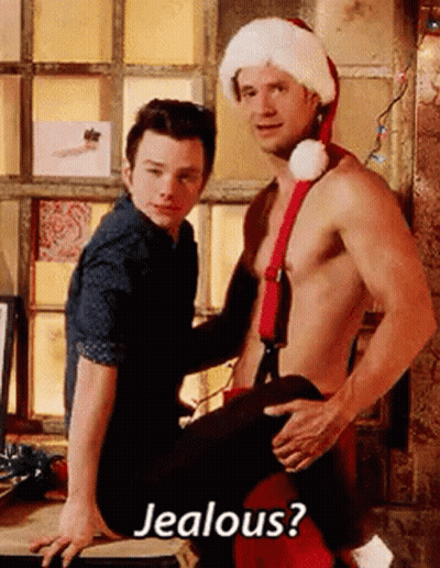 A Shirtless Man In A Santa Hat Is Sitting On A Man 'S Lap . GIF