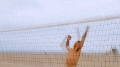 A Shirtless Man In Camouflage Shorts Stands On A Beach GIF