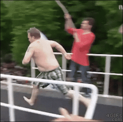 A Shirtless Man In Green Shorts Is Jumping Off A Bridge GIF