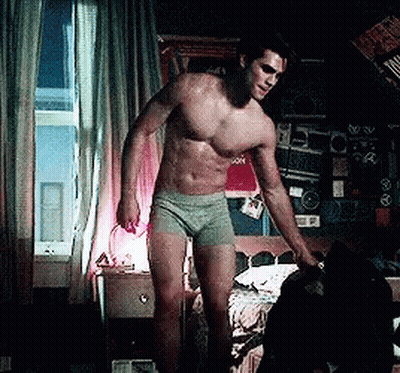 A Shirtless Man In Green Underwear Is Standing In Front Of A Bed GIF