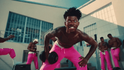 A Shirtless Man In Pink Sweats Is Lifting A Dumbbell GIF