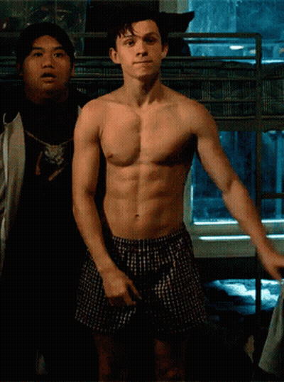 A Shirtless Man In Plaid Boxers Stands Next To Another Shirtless Man GIF