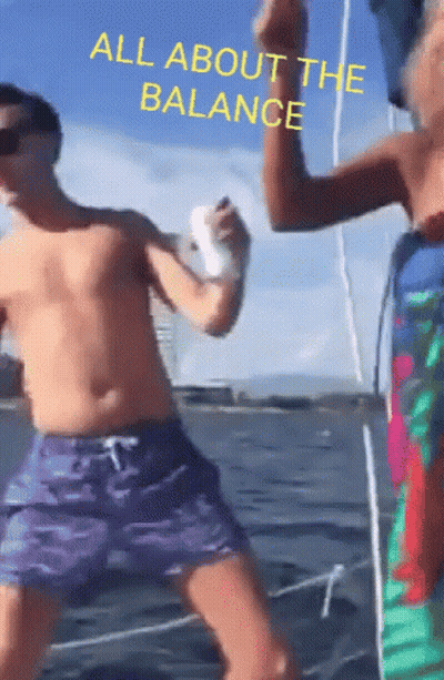 A Shirtless Man In Purple Shorts Stands Next To Another Shirtless Man In Green Shorts With The Words All About The Balan GIF