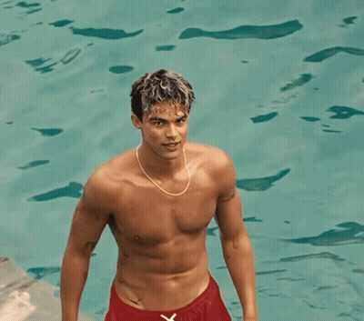 A Shirtless Man In Red Shorts Is Standing In A Pool GIF