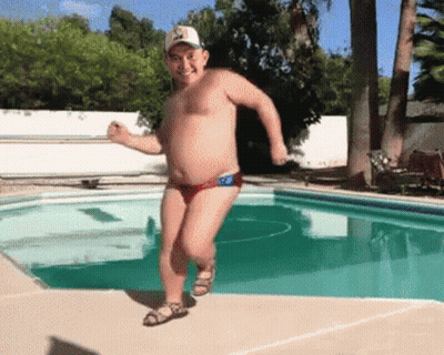 A Shirtless Man In Red Swim Trunks And A Hat Is Running By A Pool GIF