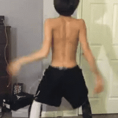 A Shirtless Man In Shorts Is Dancing In Front Of A Door GIF
