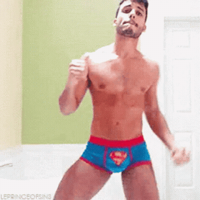 A Shirtless Man In Superman Underwear Is Dancing In A Room . GIF