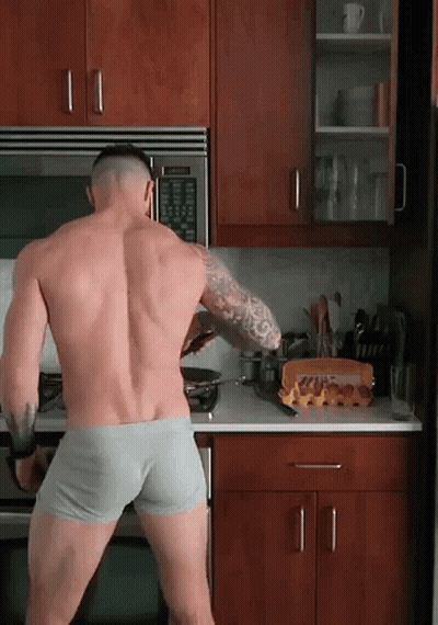 A Shirtless Man In Underwear Is Standing In A Kitchen Cooking GIF