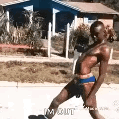 A Shirtless Man In Underwear Is Walking Down A Sidewalk In Front Of A House . GIF