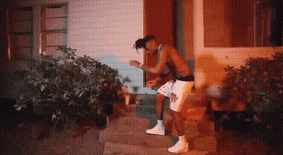 A Shirtless Man In White Shorts Is Standing In Front Of A House GIF